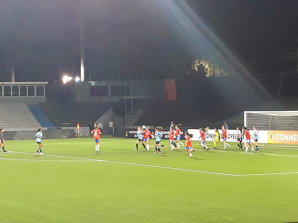 Hinchas viendo un partido decisivo en un bar deportivo con pantallas gigantes